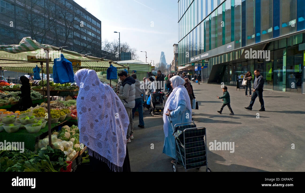 Muslim woman with headscarf shopping for fruit and veg in Whitechapel Road street market in East London E1 UK   KATHY DEWITT Stock Photo