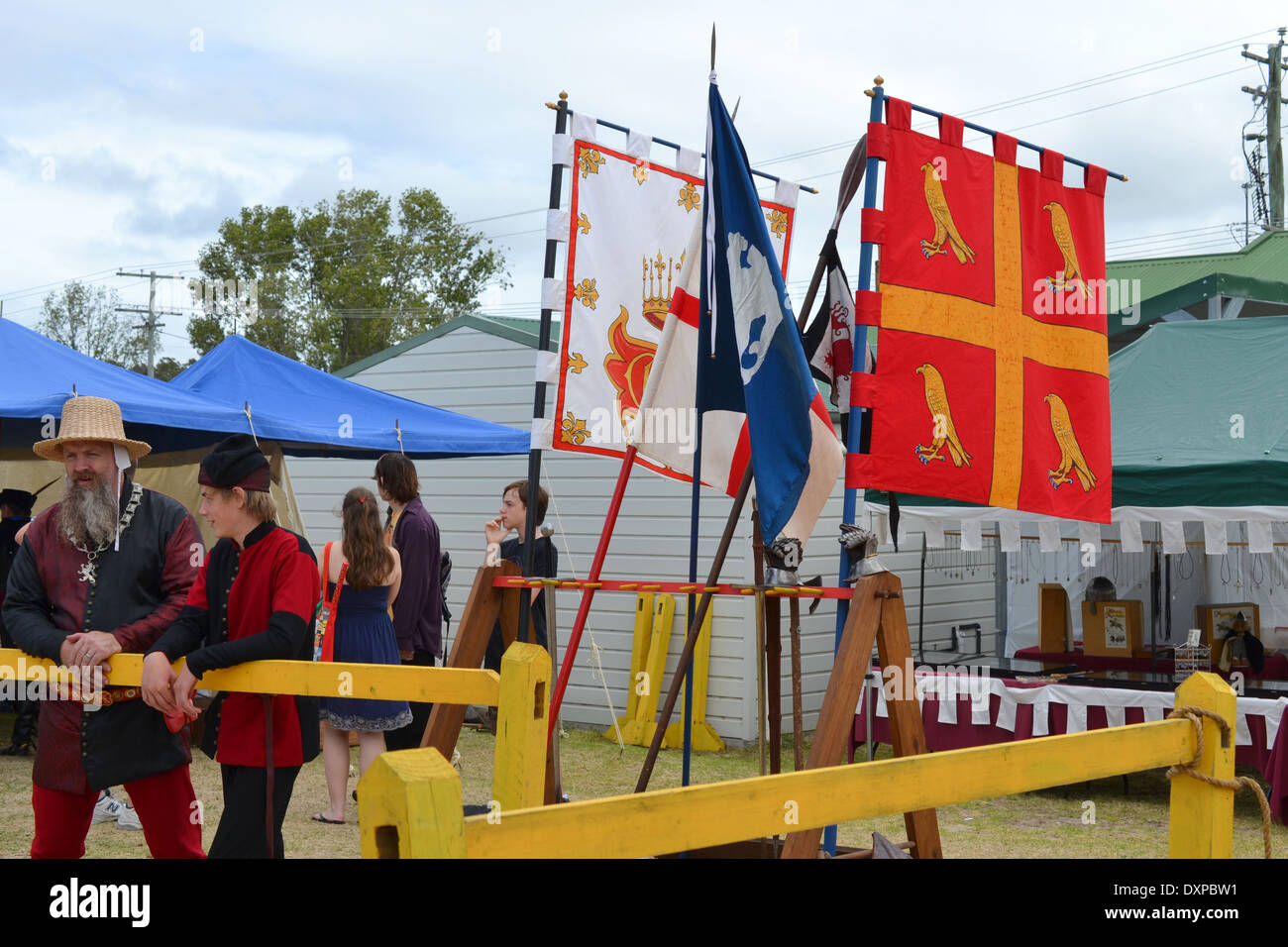 People watch a performance in front of family crest flags at medieval festival Stock Photo