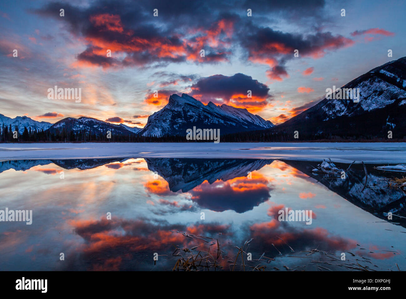 Sunrise in Banff National Park.  Dawn glows in the clouds above Mount Rundle and is reflected in Vermilion Lake. Stock Photo