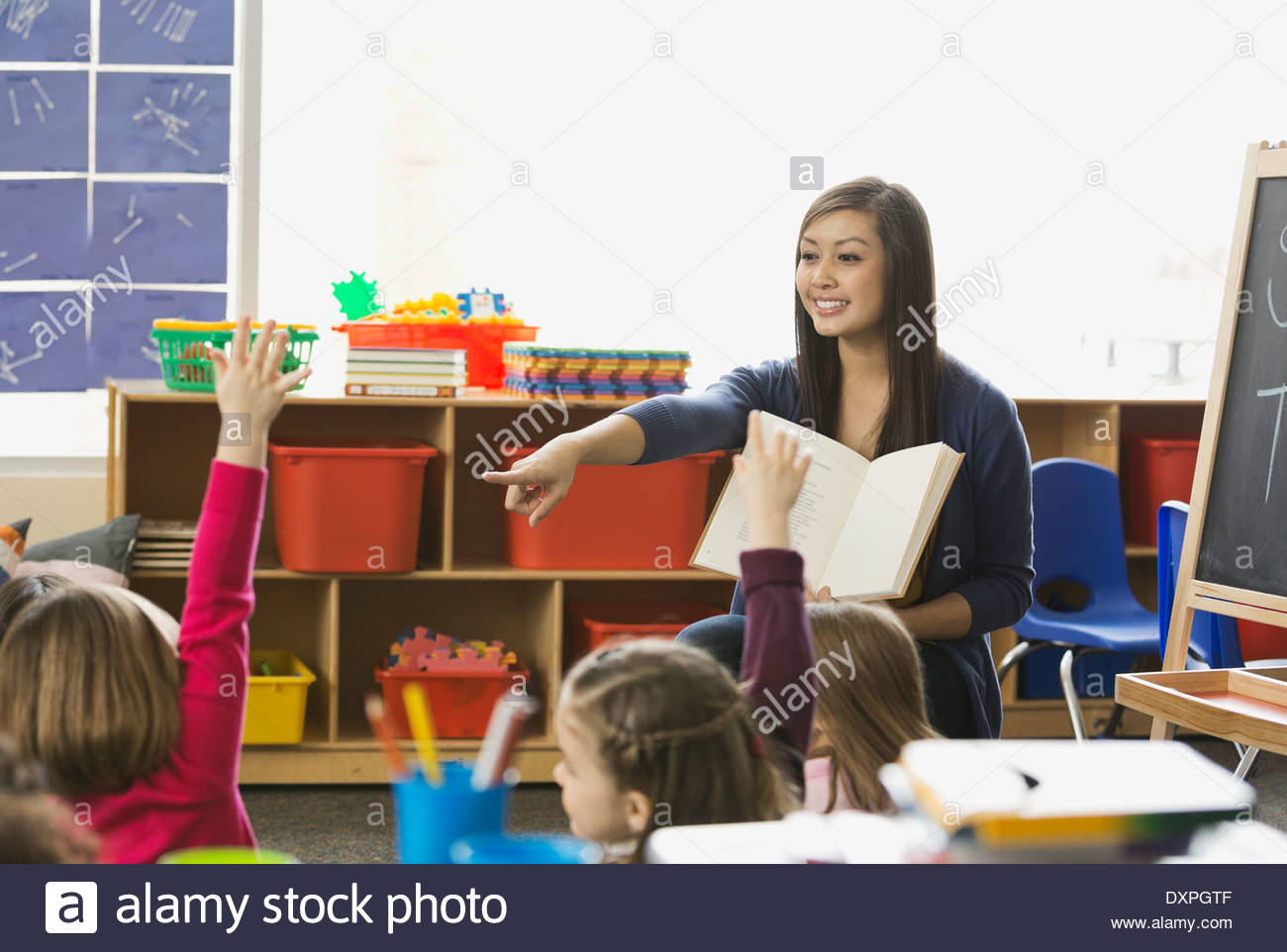Teacher pointing at student with hands raised in class Stock Photo