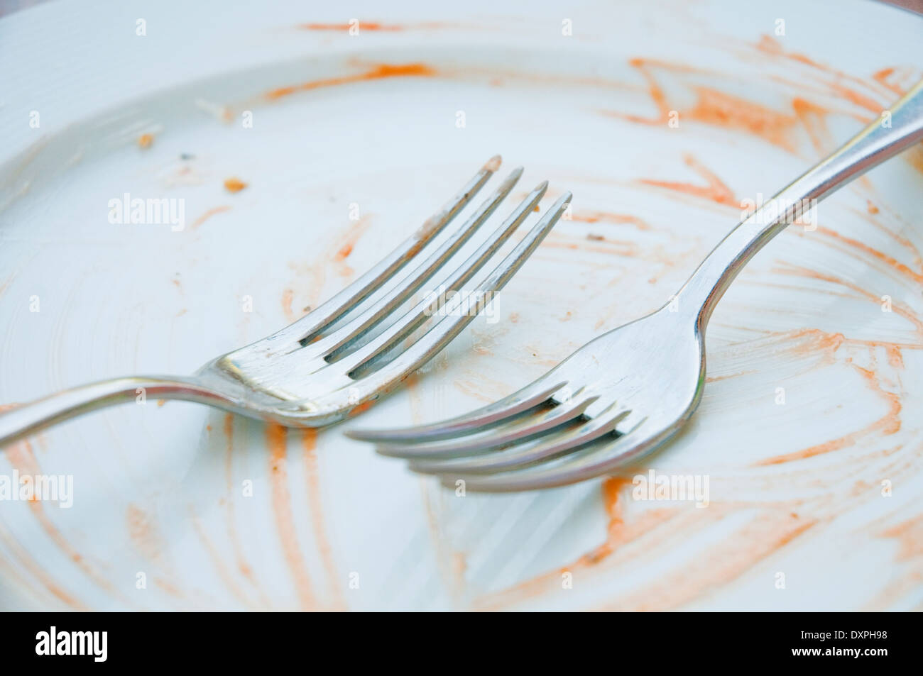 Two forks on an empty plate after eating. Stock Photo