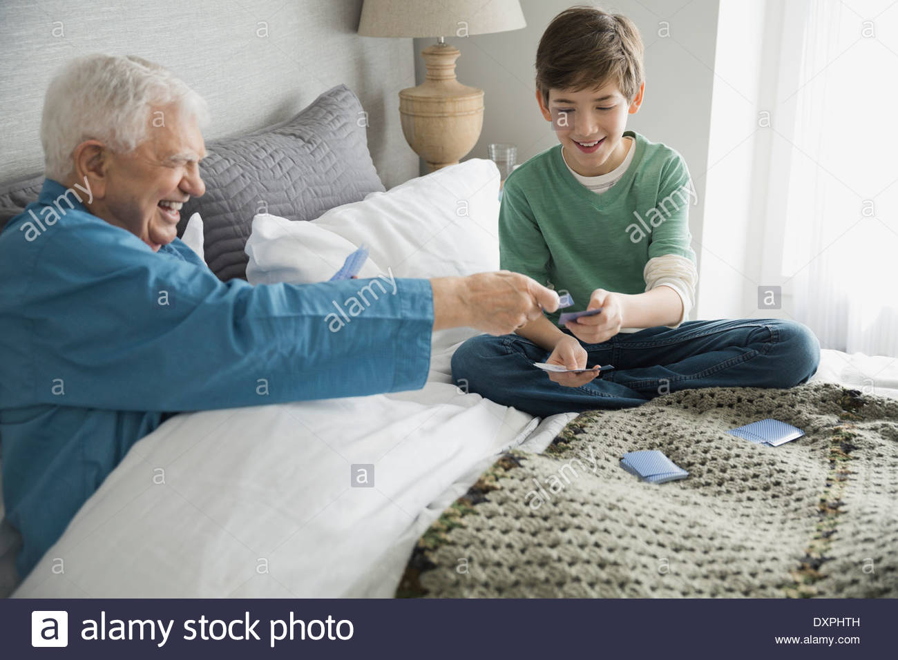 Grandfather and grandson playing cards in bedroom Stock Photo