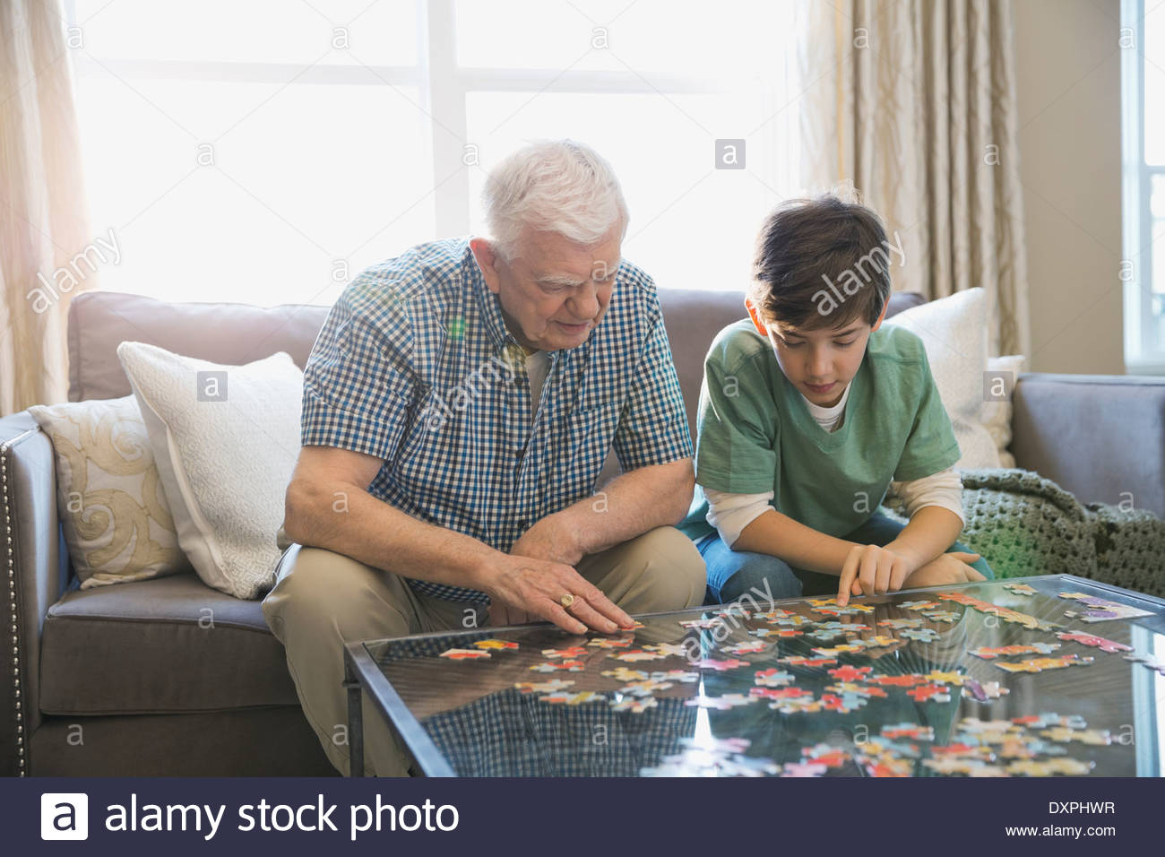 Grandfather and grandson solving puzzle in living room Stock Photo