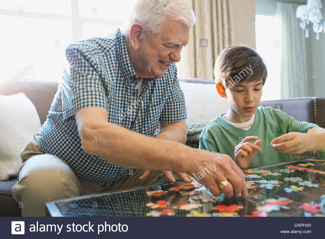 Grandfather and grandson solving puzzle at table Stock Photo