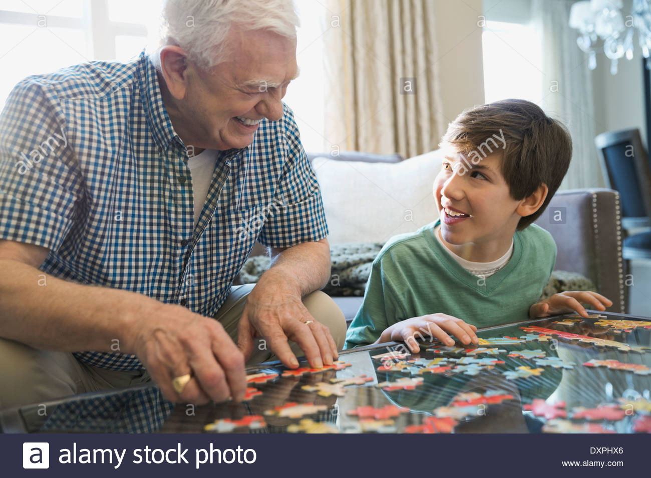Smiling grandfather and grandson solving puzzle at home Stock Photo
