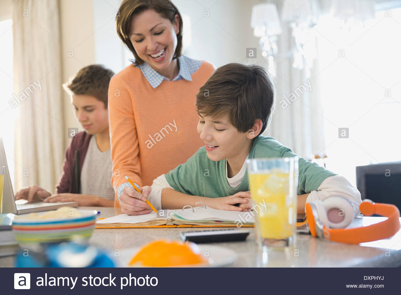 Smiling woman assisting son with homework Stock Photo