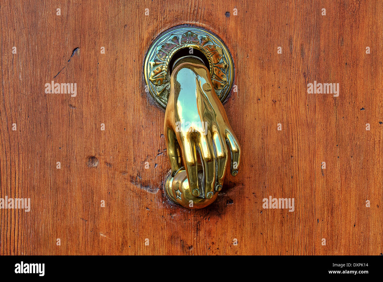 Hand shaped golden door knob on brown wooden door on Valencia, Spain