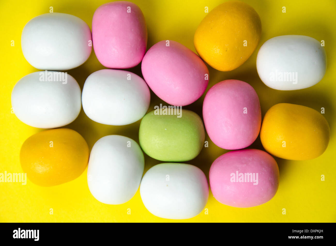 Close up of candy in different colours at a yellow background Stock Photo