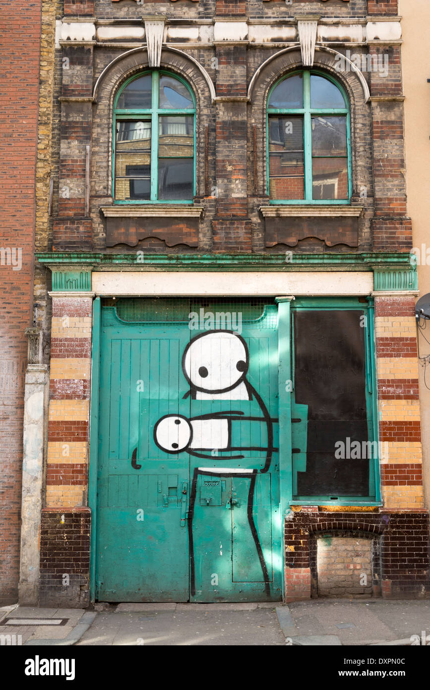 Graffiti by Stik on door in Pitfield Street near Old Street, Hoxton, London, England, UK Stock Photo