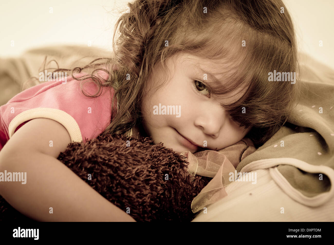 Sad little girl lying in bed colortoned Stock Photo