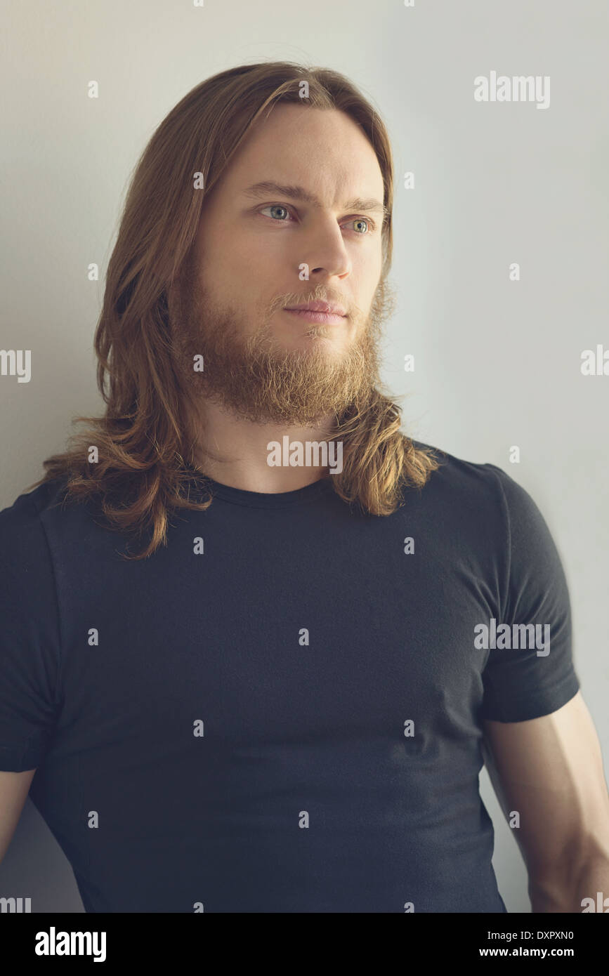 A medium length hair man with beard portrait in natural light Stock Photo