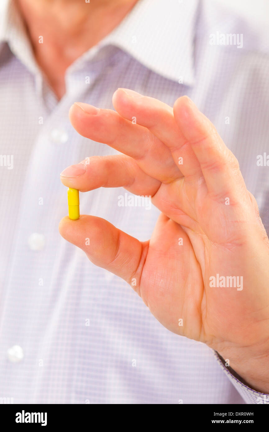 Senior adult man holds medicine capsule in his hand and shows to camera close up. Stock Photo