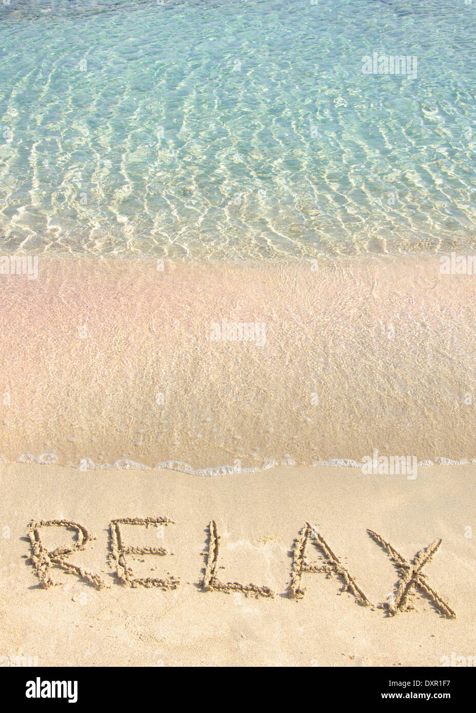 Relax word written in the sand, on a beautiful beach with clear blue