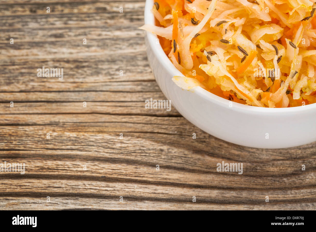 sauerkraut salad with carrot, caraway seeds and olive oil - a small bowl against grained wood Stock Photo