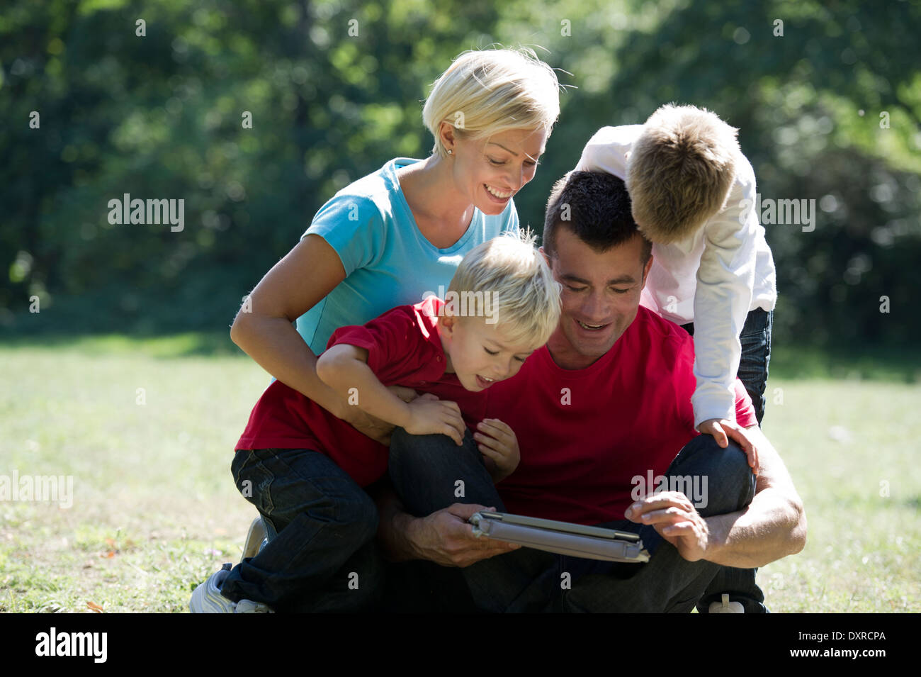 Young family looking at tablet computer in the park Stock Photo