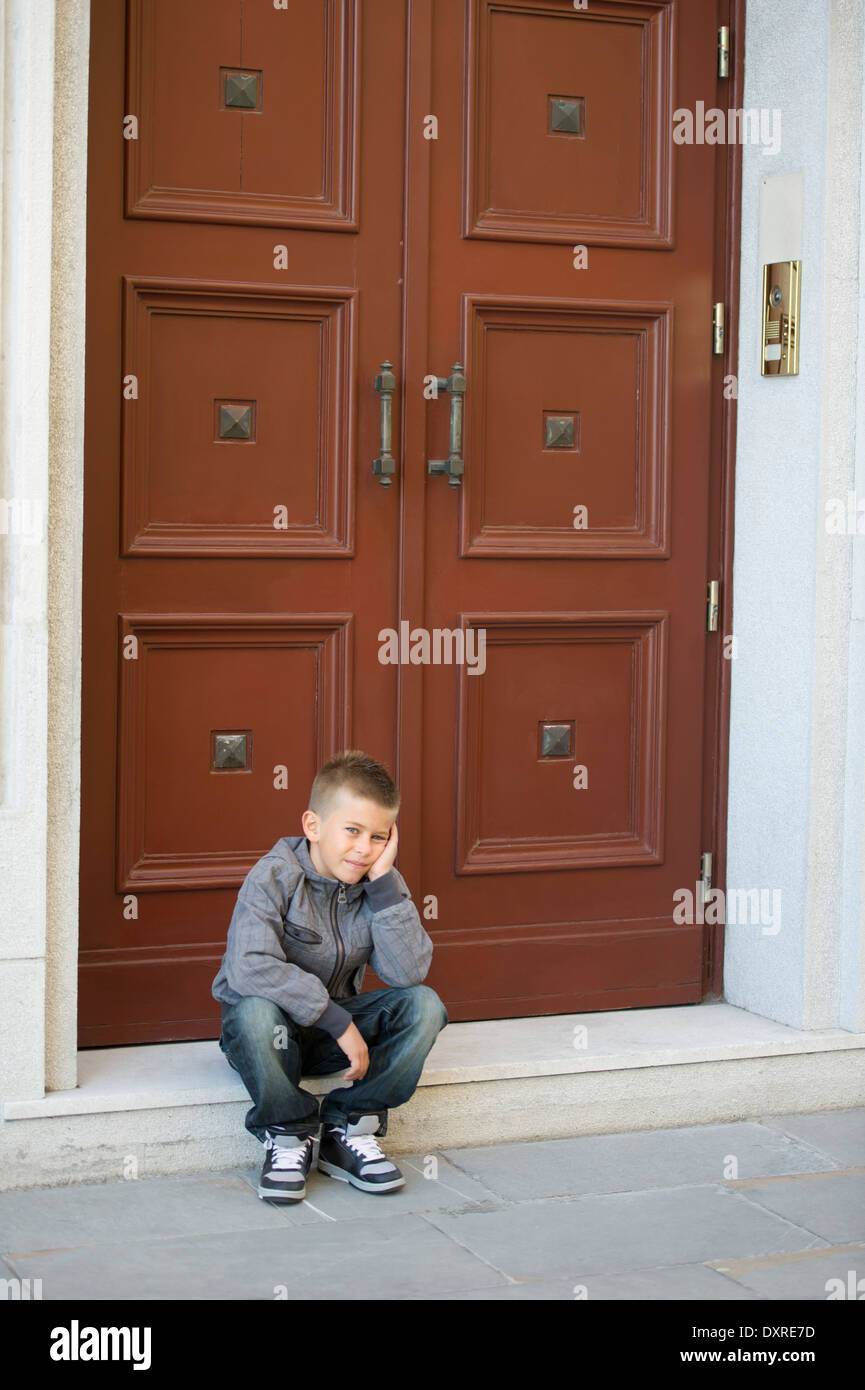 Young boy sitting on doorstep Stock Photo