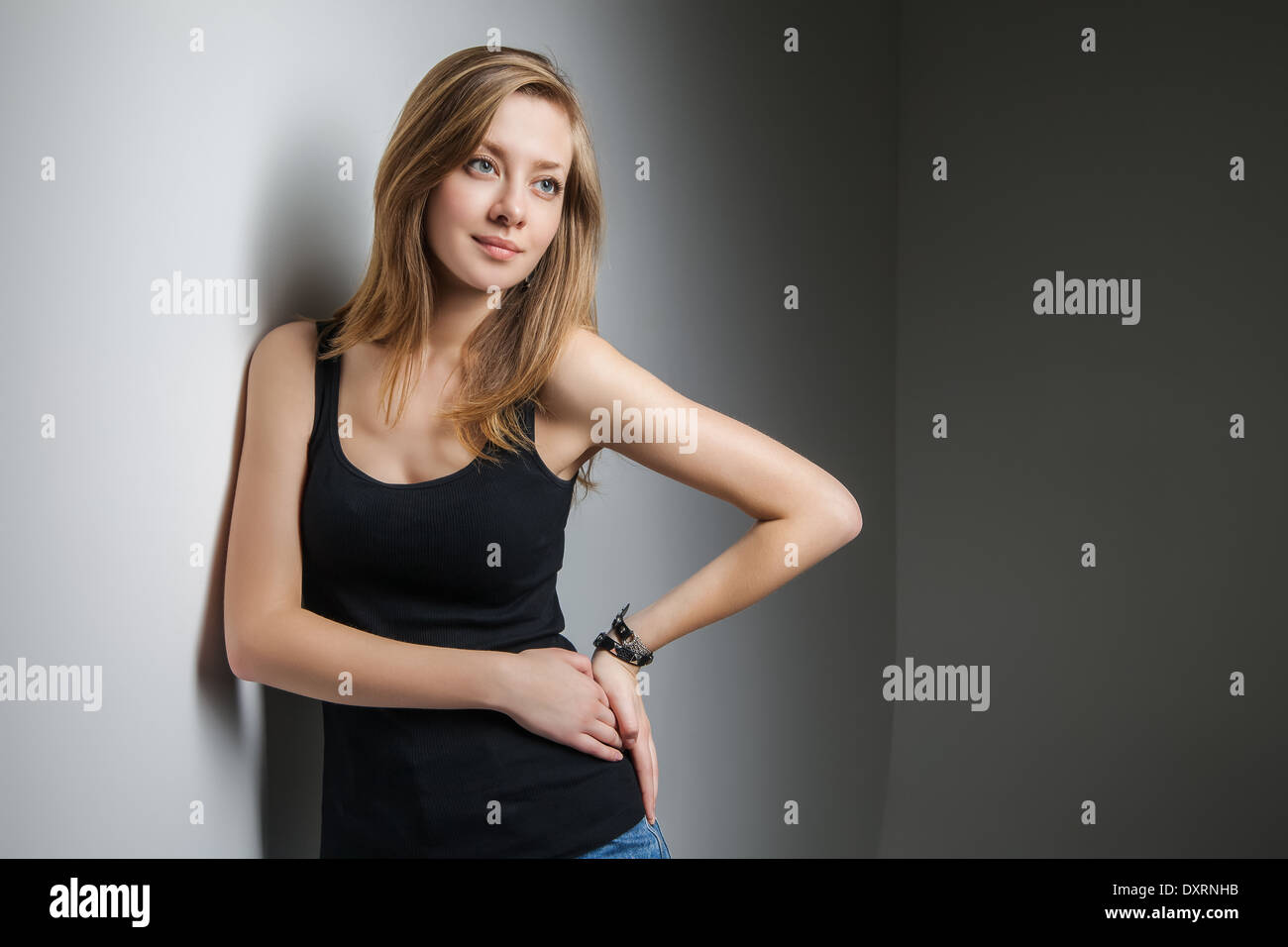 Beautiful young woman wearing jeans and black t-shirt over gray background Stock Photo