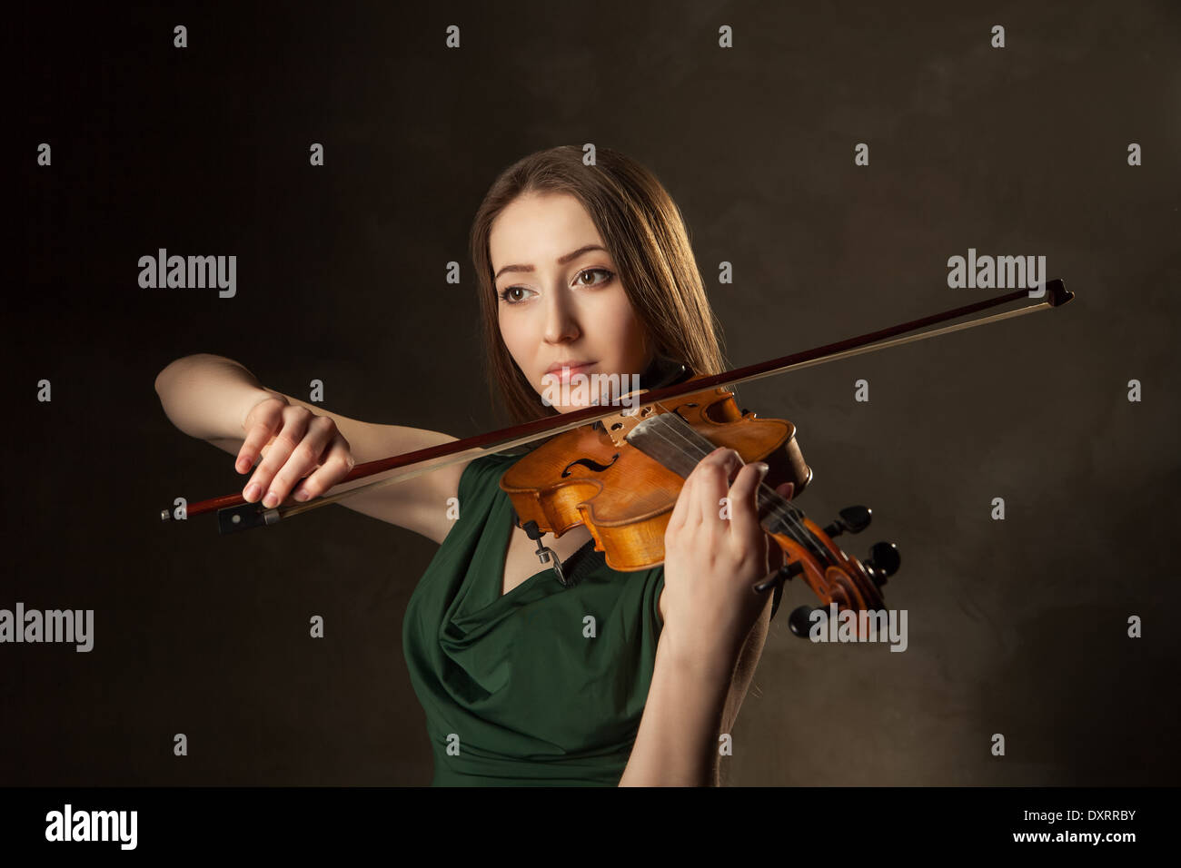 Beautiful young woman playing violin over black background Stock Photo
