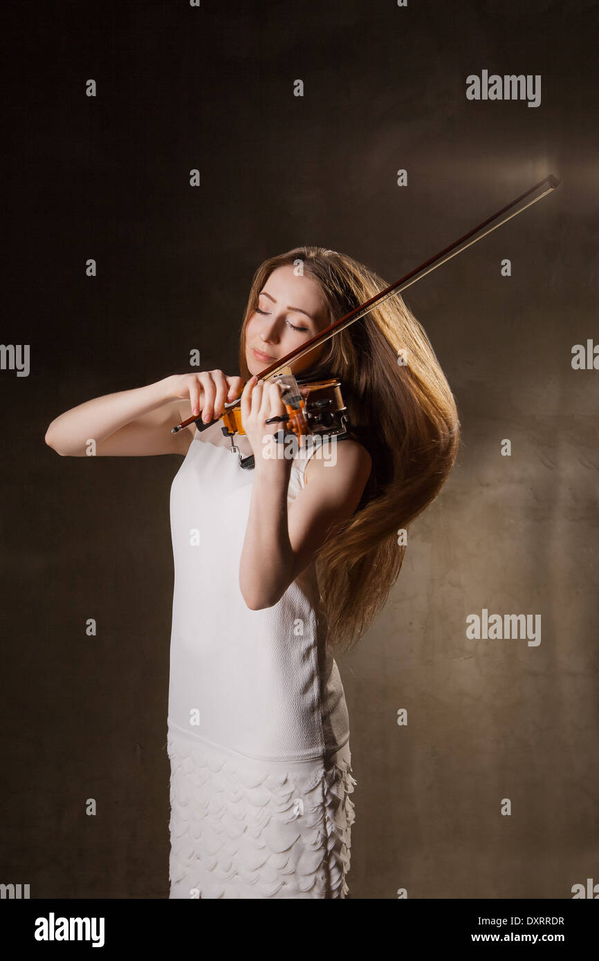 Beautiful young woman playing violin over black background Stock Photo ...