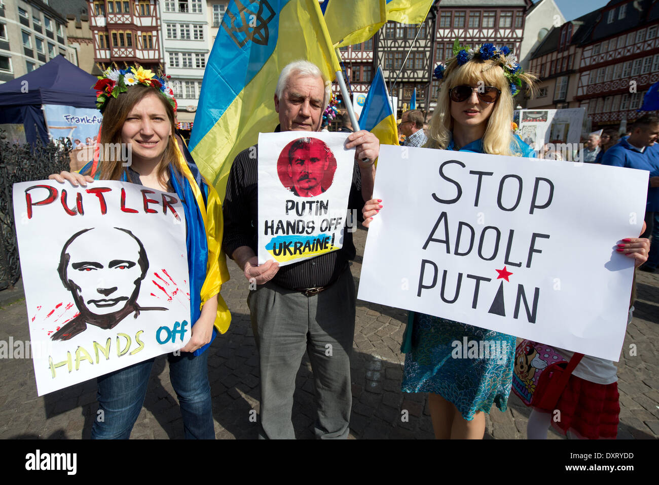 Frankfurt, Germany. 30th Mar, 2014. A Ukrainian demonstrators hold up posters which read 'Putler Hands off' (L-R), 'Putin hands off Ukraine' and 'Stop Adolf Putin' during a rally with several hundred Ukrainian demonstrators in Frankfurt, Germany, 30 March 2014. Demonstrators protested against the Russian occupation of the Crimea and in support of Ukrainian independence. Photo: Boris Roessler/dpa/Alamy Live News Stock Photo