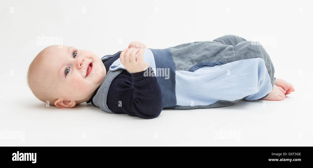 baby boy laying on floor. neutral grey background. studio shot Stock Photo