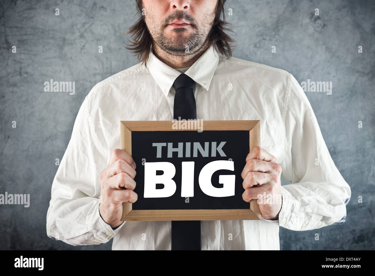 Businessman holding blackboard with THINK BIG title. Business concept. Stock Photo