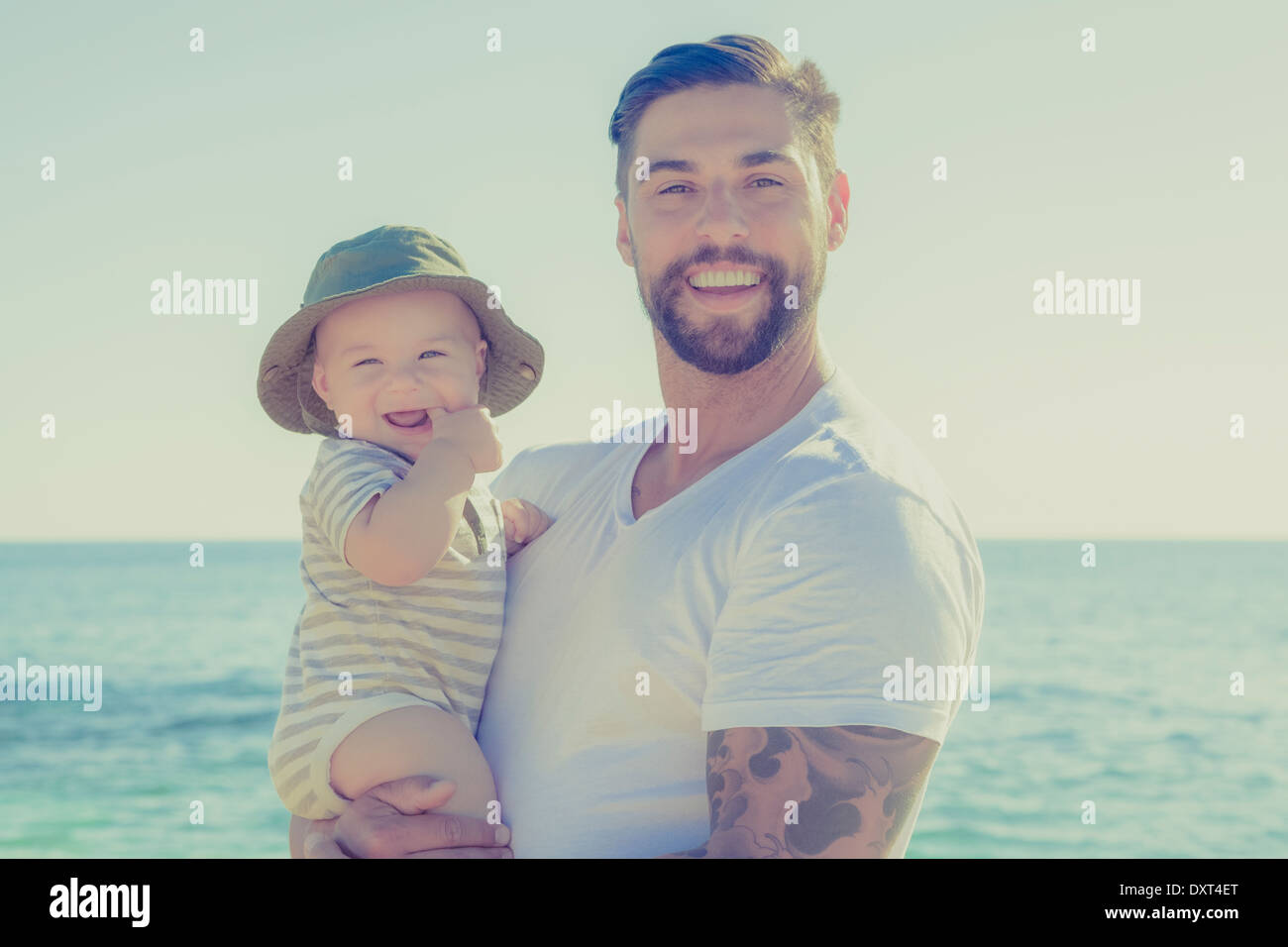 Portrait of father and baby son smiling on sunny beach Stock Photo