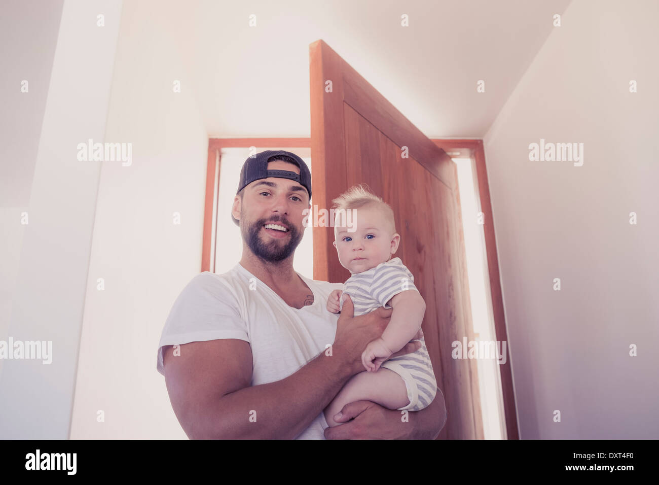 Portrait of smiling father holding baby son in doorway Stock Photo
