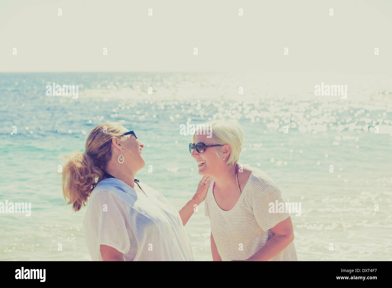 Women laughing on sunny beach Stock Photo