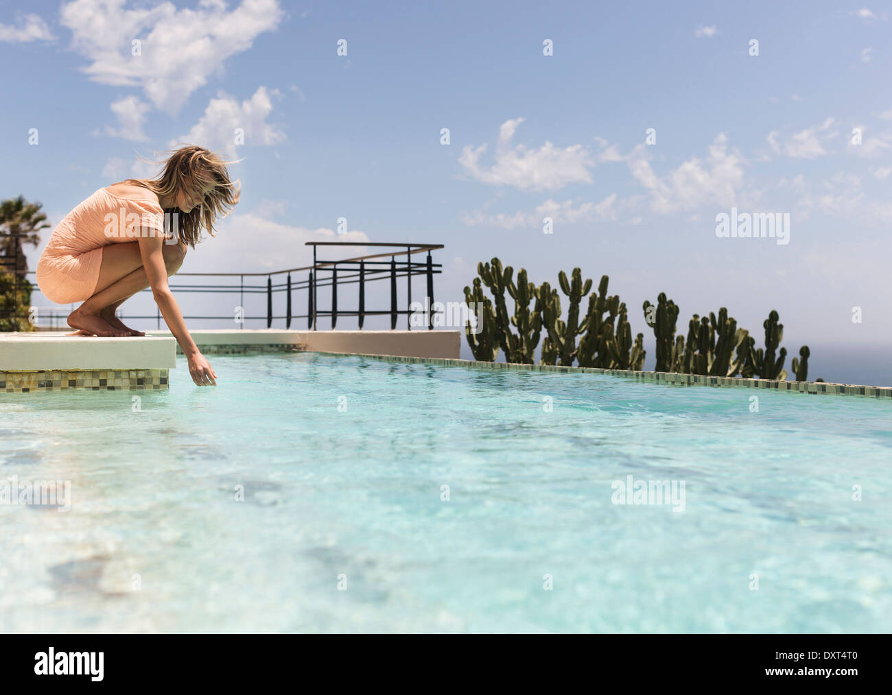 Woman dipping hand in swimming pool Stock Photo
