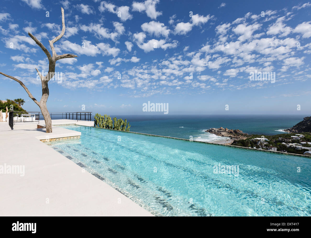 Clouds in blue sky over luxury lap pool overlooking ocean Stock Photo