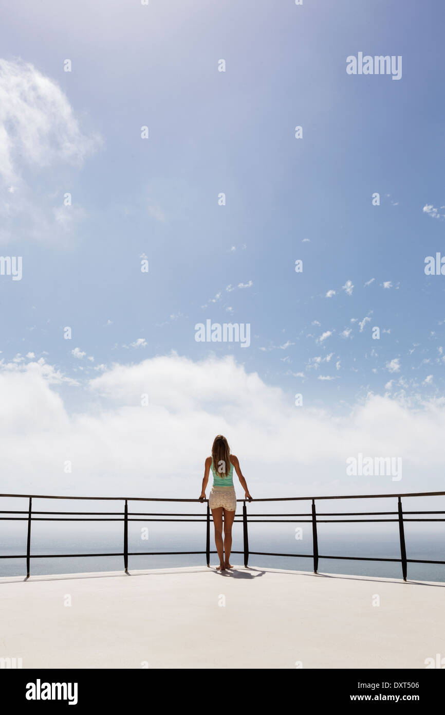 Woman standing on balcony overlooking ocean Stock Photo