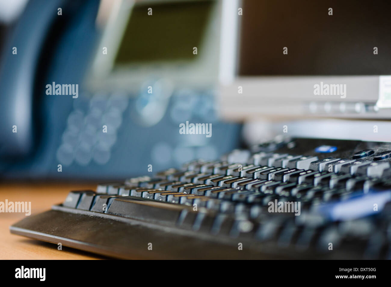 Computer keyboard on an office desk with telephone and monitor Stock Photo