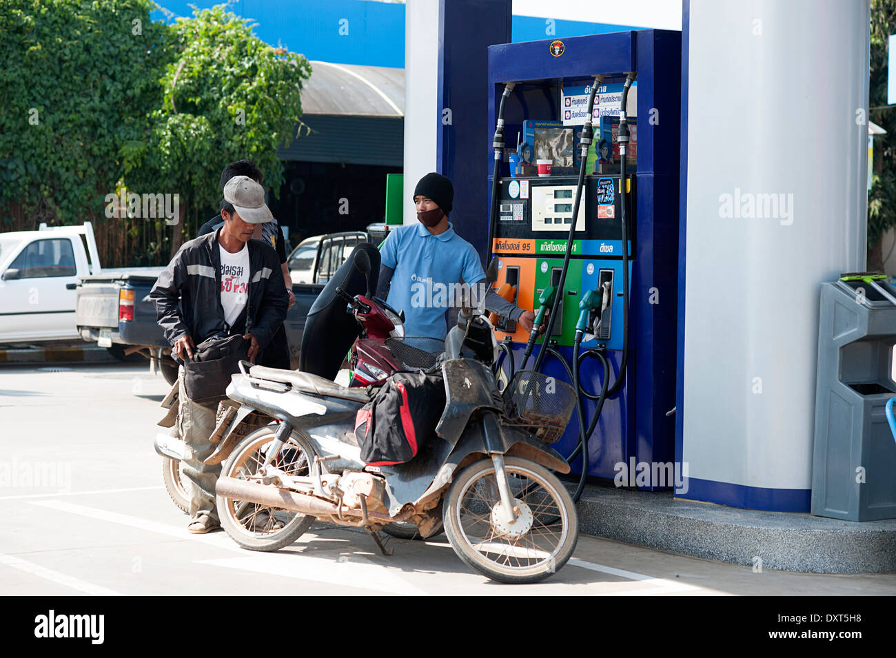 Two men stop at the petrol station to fill up with gas. Northern Thailand, Asia. Stock Photo