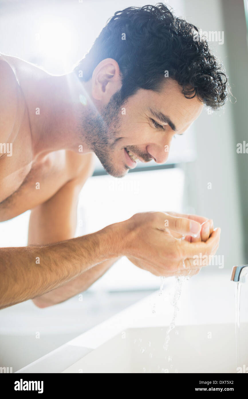 Close up of man washing face at sink Stock Photo