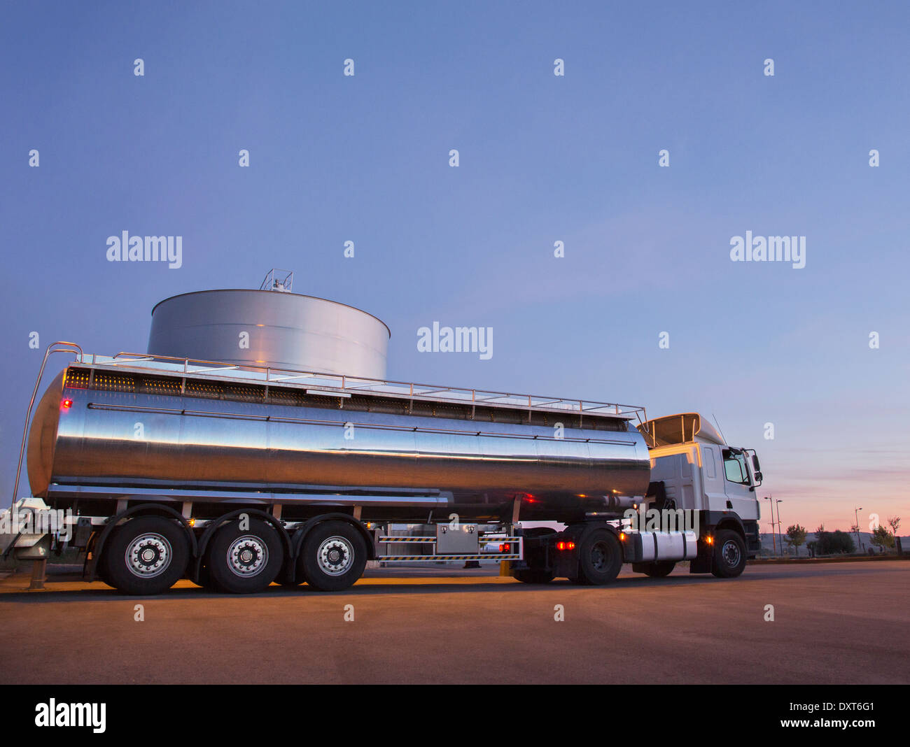 Stainless steel milk tanker next to silage storage tower Stock Photo