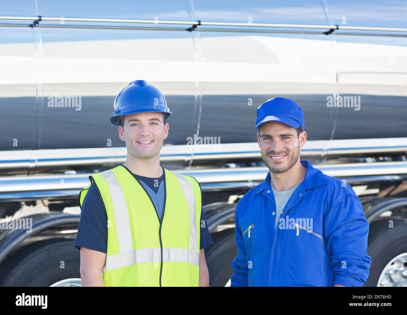 Portrait of confident workers next to stainless steel milk tanker Stock Photo