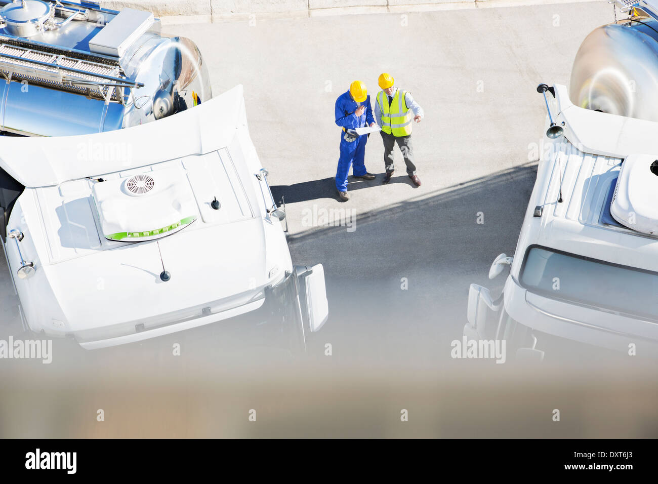 Workers reviewing paperwork near milk tankers Stock Photo