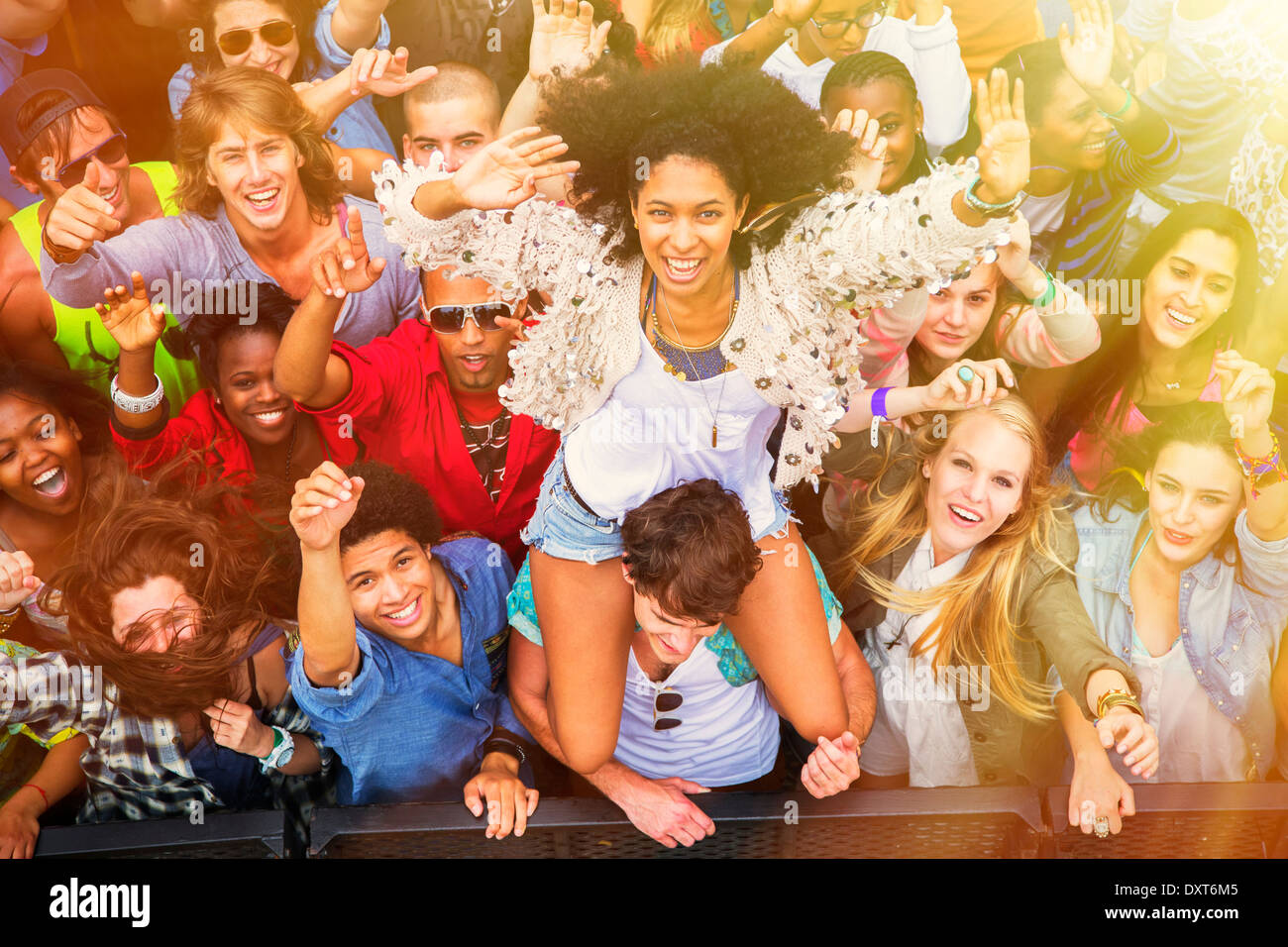 Cheering woman on manÍs shoulders at music festival Stock Photo