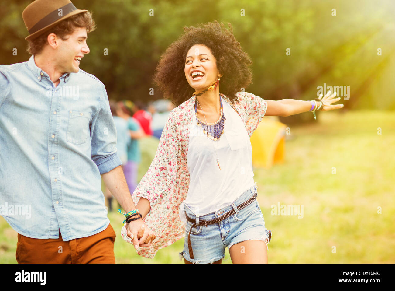 Happy couple in field outside tents at music festival Stock Photo