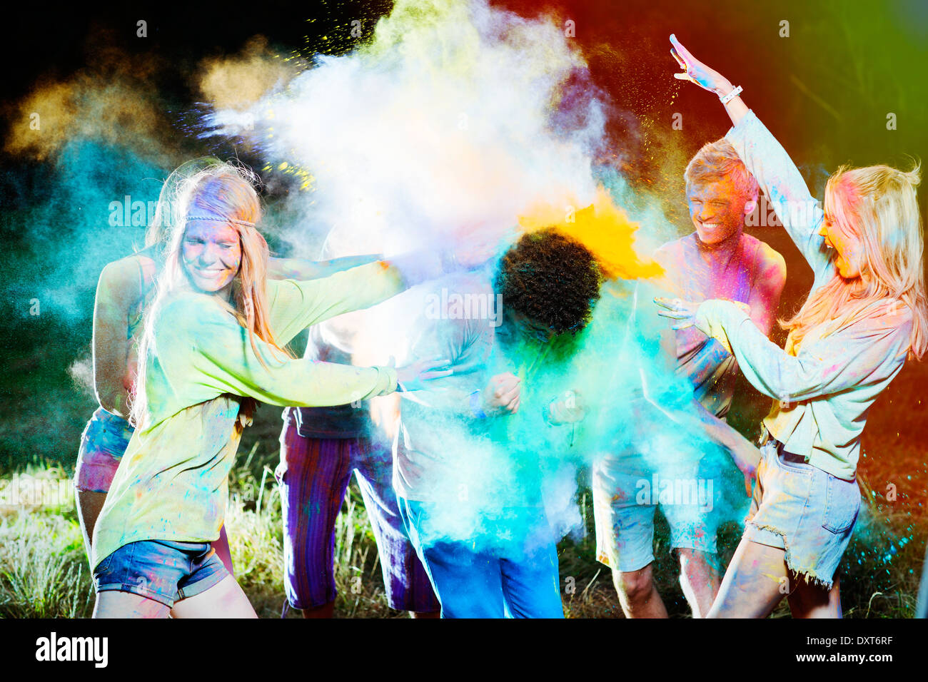 Friends throwing chalk dye on man at music festival Stock Photo