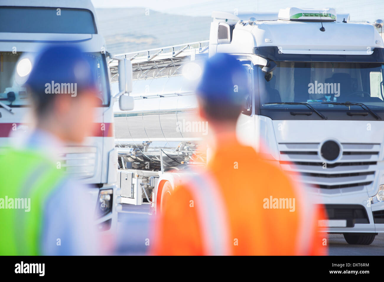 Workers looking at stainless steel milk tankers Stock Photo