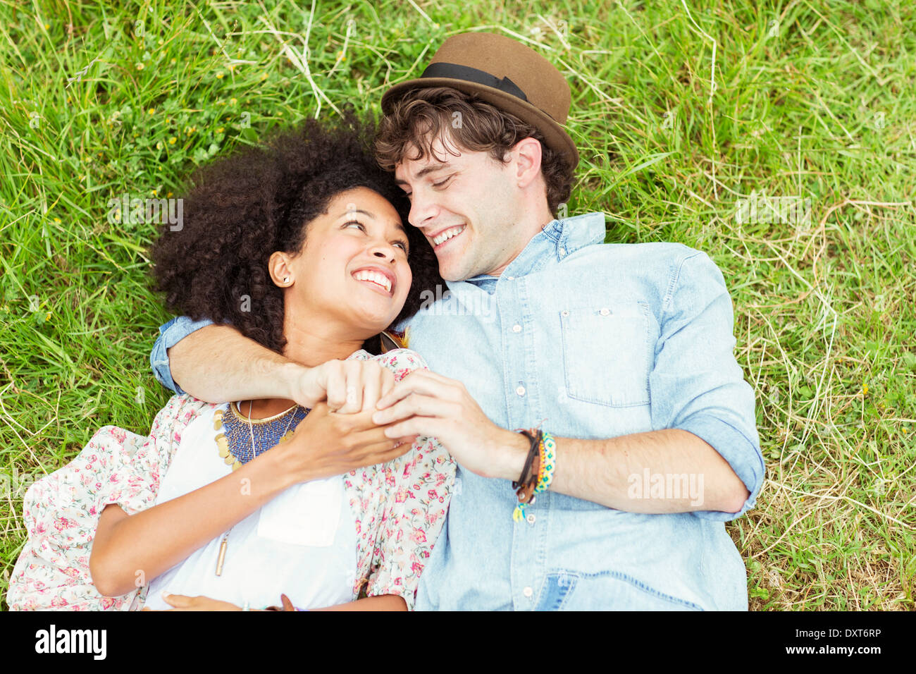 Happy couple holding hands and laying in grass Stock Photo