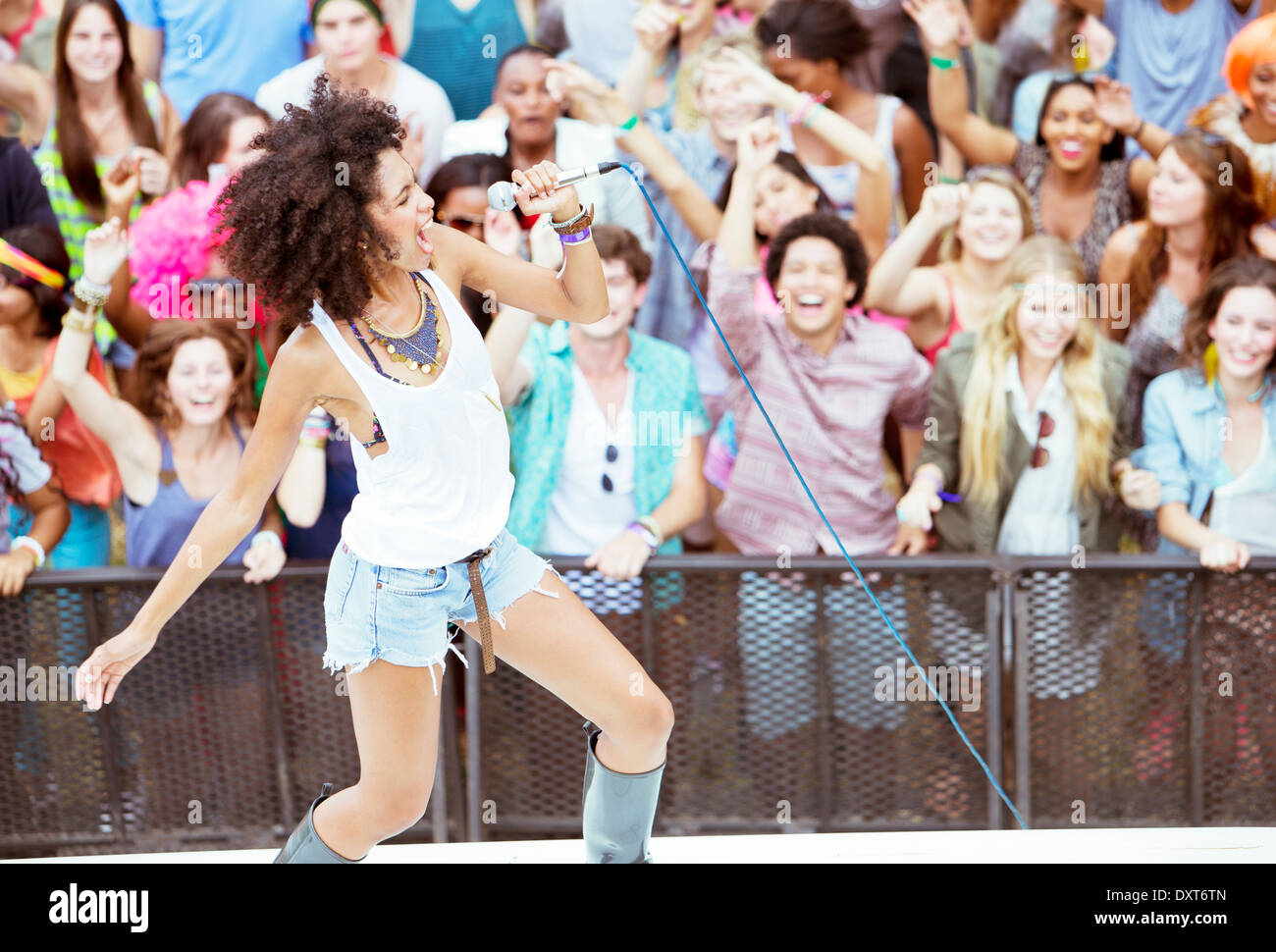 Fans cheering for performer singing on stage at music festival Stock Photo