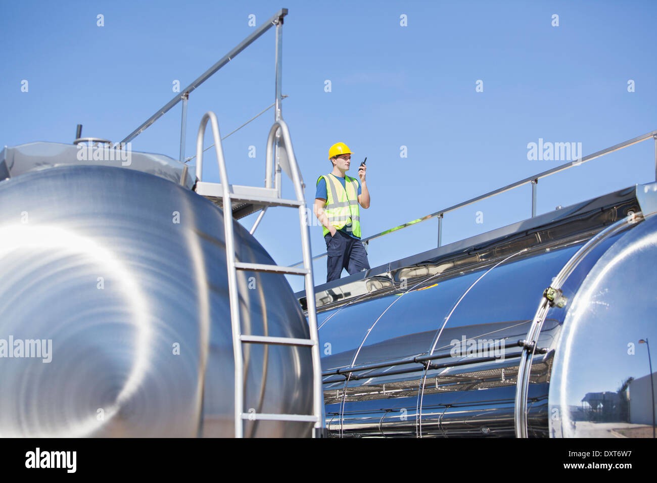 Worker using walkie-talkie on platform above stainless steel milk tanker  Stock Photo - Alamy