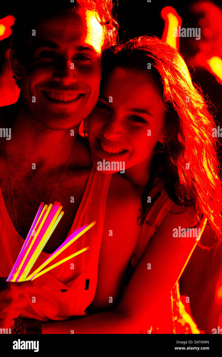Close up portrait of happy couple with glow sticks at music festival Stock Photo