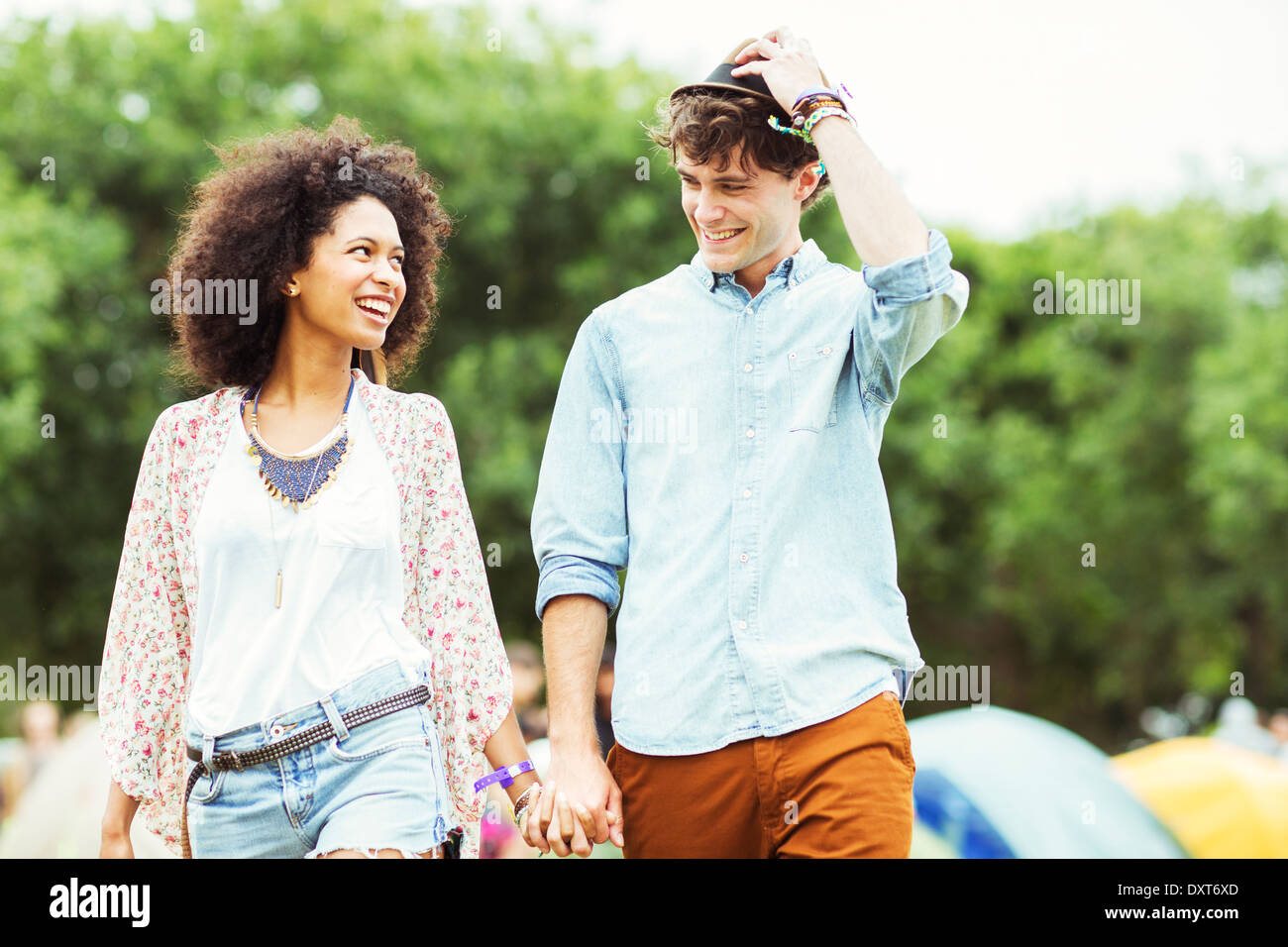 Couple holding hands outside tents at music festival Stock Photo