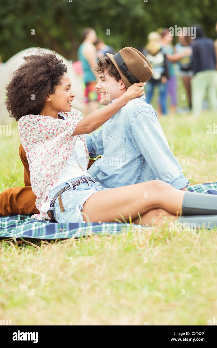 Couple hugging on blanket in grass at music festival Stock Photo