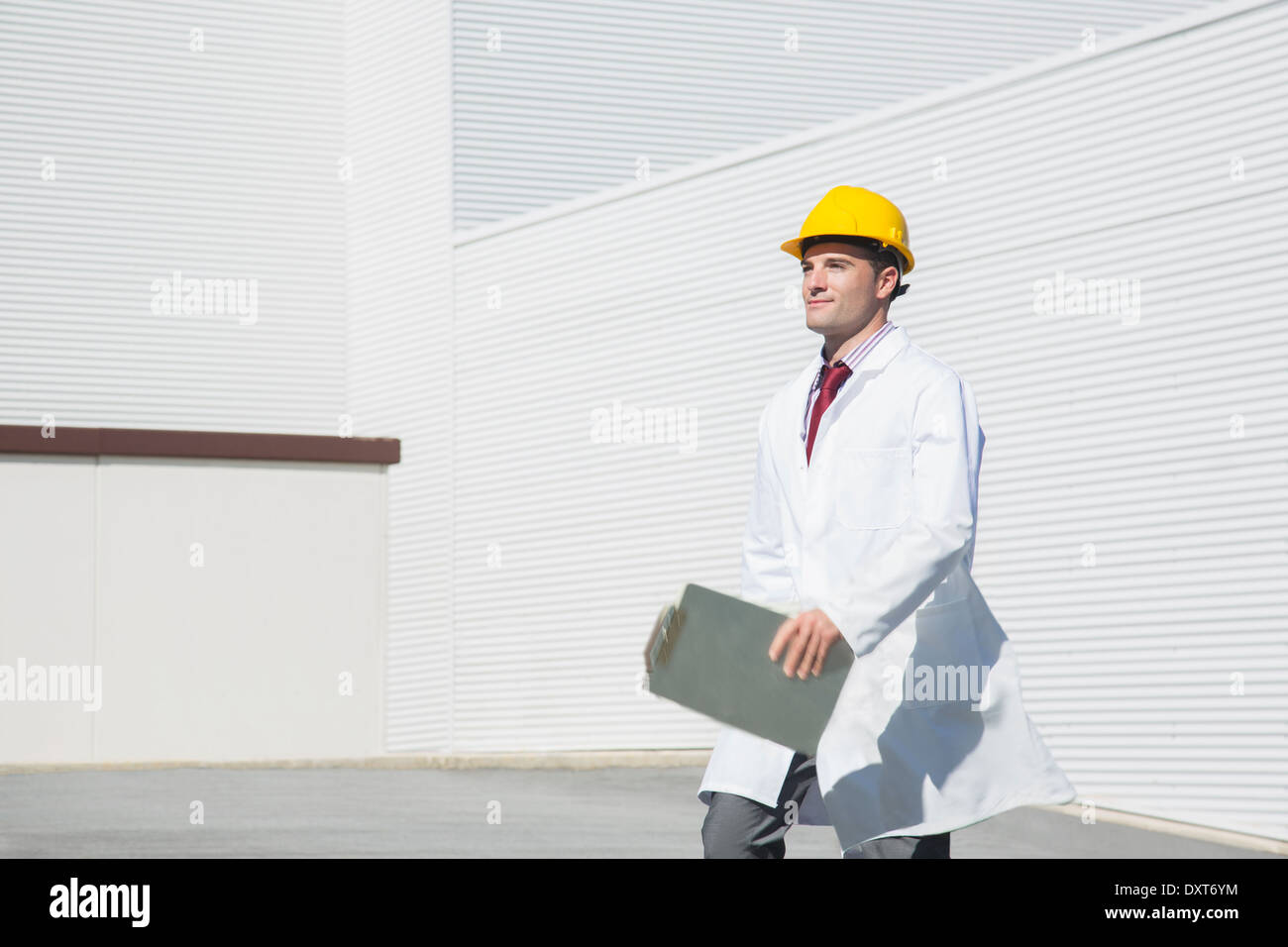Scientist in hard-hat with clipboard walking outdoors Stock Photo