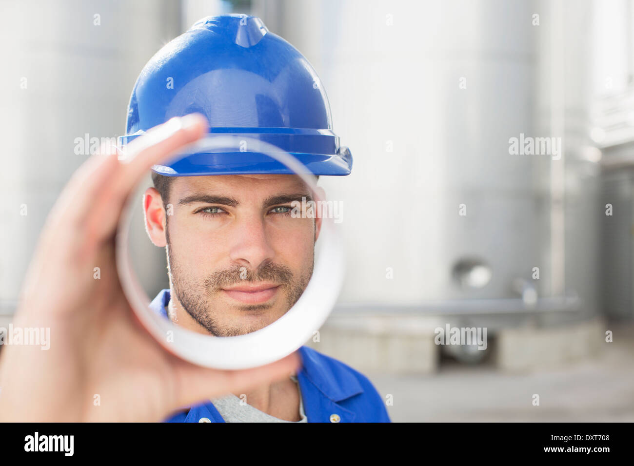 Portrait of worker looking through metal tube Stock Photo